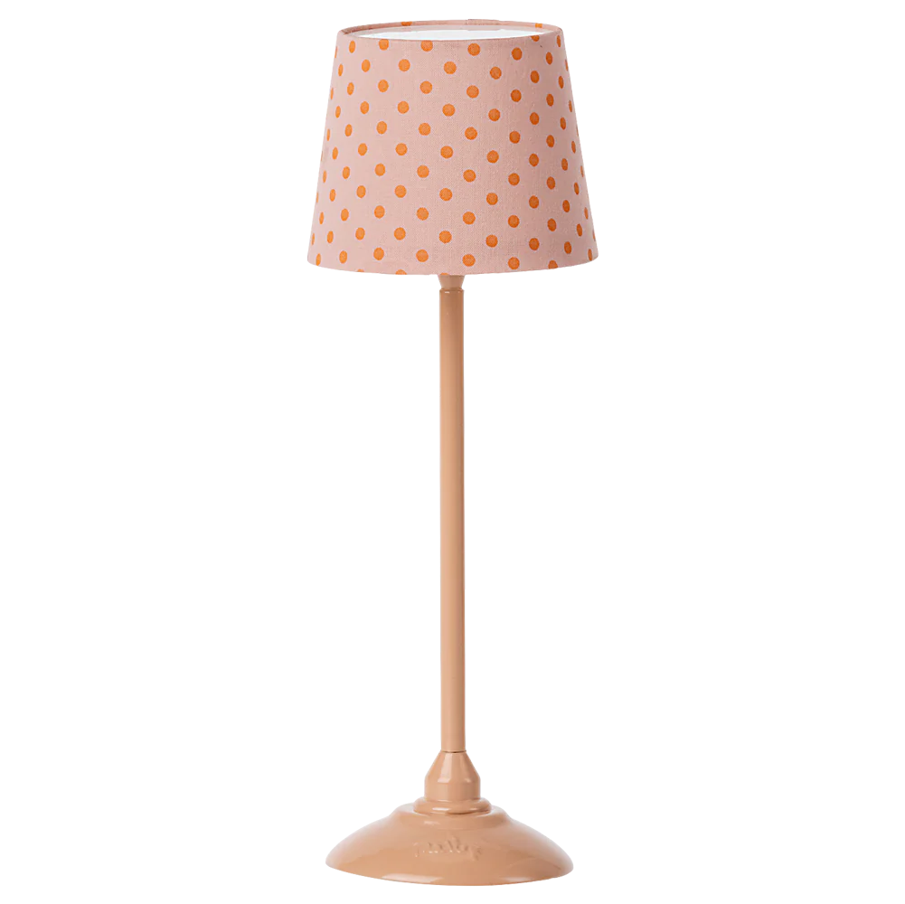 A miniature floor lamp with a pink polka-dotted shade and a beige base, turned on with a soft light.