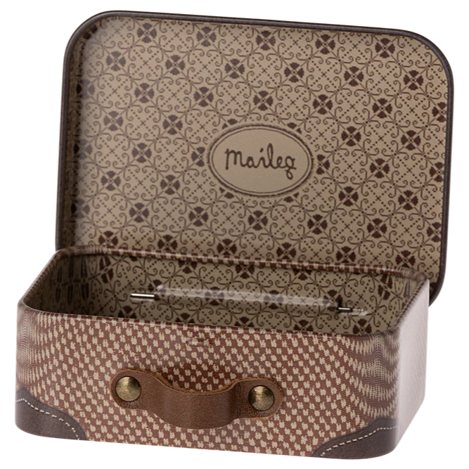 A small, brown Maileg metal suitcase with a geometric pattern, open and empty, showing the brand name on the interior lid.
