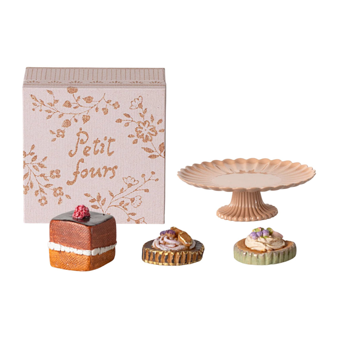Set of miniature pastries and a cake stand with a 'Petit fours' box on a white background