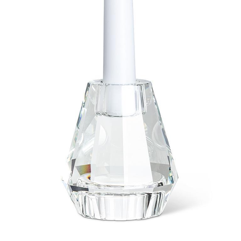 A clear faceted glass candle holder with a white candle inserted, photographed on a clean white background.