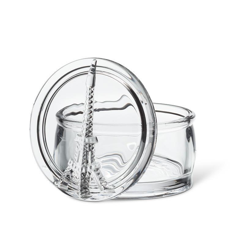 A clear glass round container with a matching glass lid featuring a sculpted Eiffel Tower design, shown on a white background.