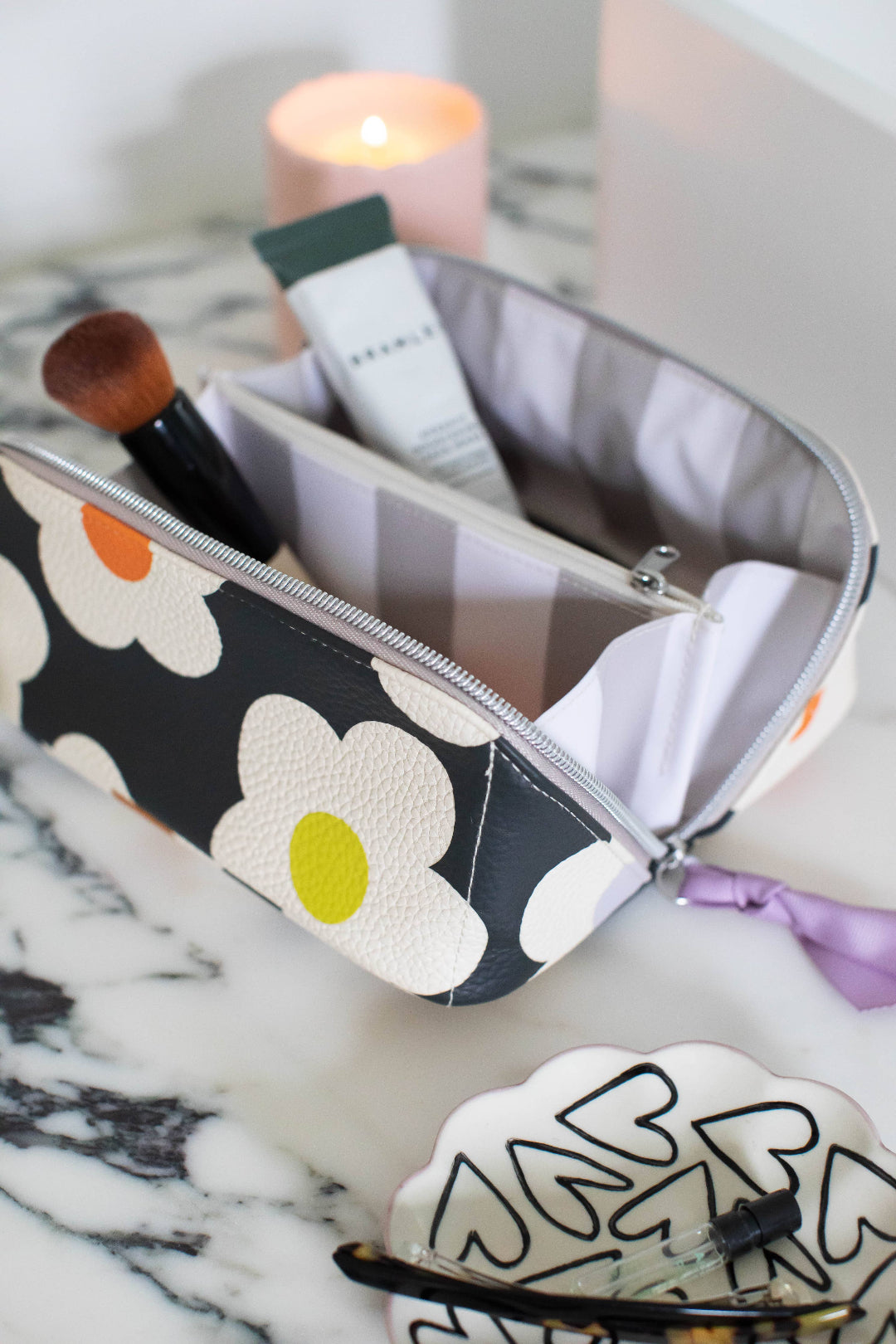 Makeup bag with floral design on a marble surface with makeup items inside