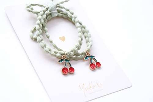 Set of braided bracelets with cherry charms on a white card