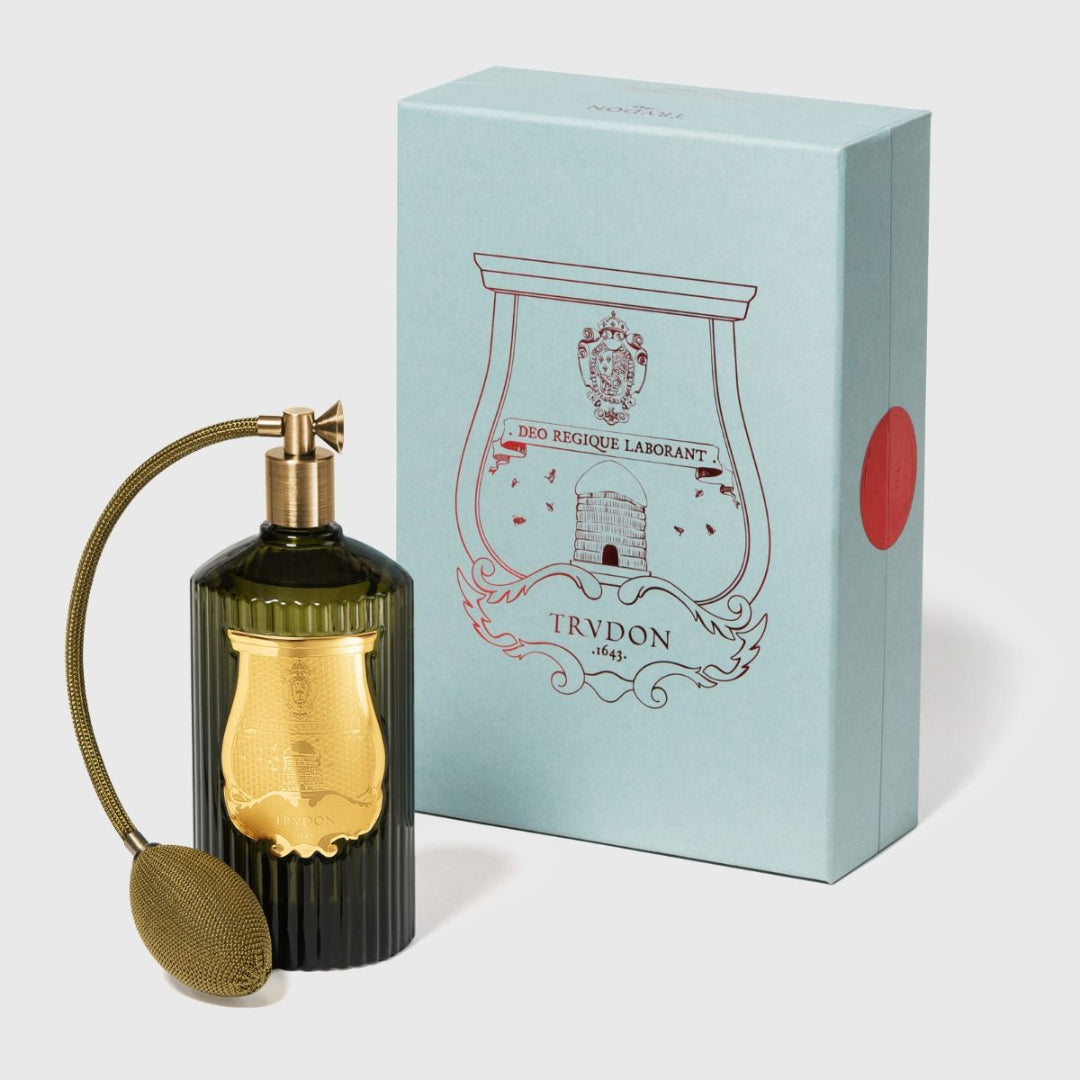 Trudon Room Spray bottle with gold cap and decorative label next to its packaging box on a light background