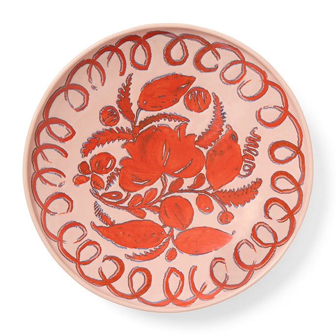Pink decorative plate with red floral design on a white background