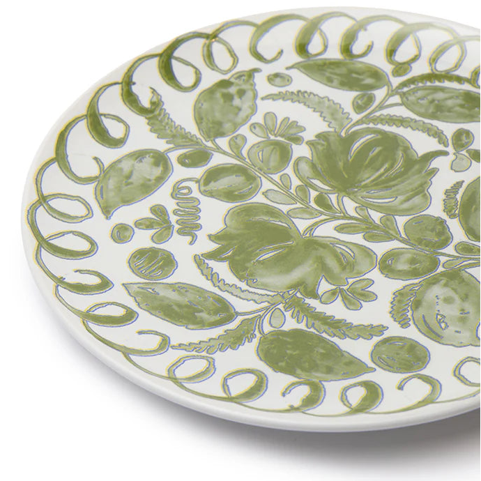 A close-up of a white ceramic plate decorated with a hand-painted green botanical pattern of leaves, flowers, and scrolling borders, set against a plain white background.