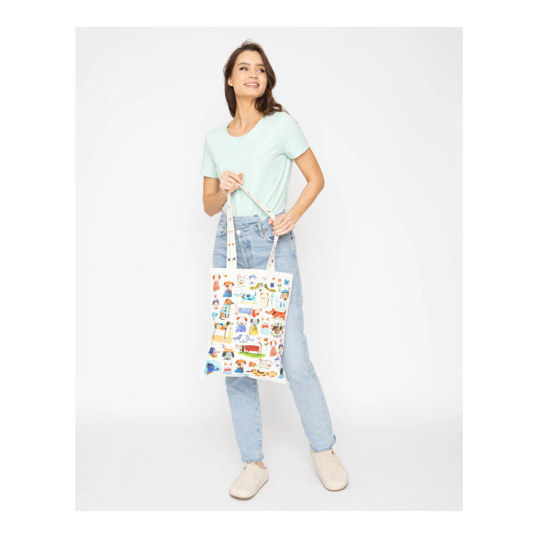 Woman holding a colorful tote bag with various designs on a white background