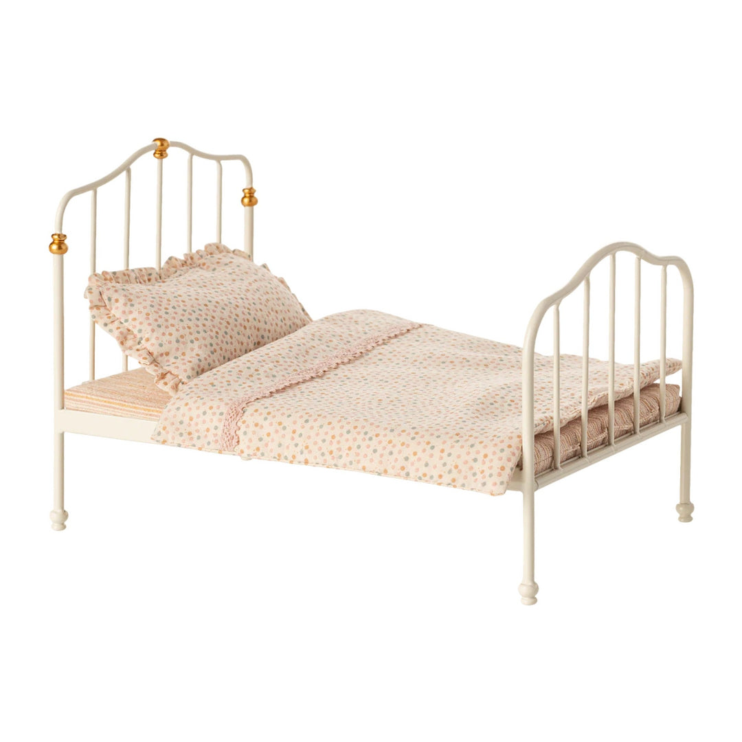 Small bed with beige metal frame and bedding on a white background