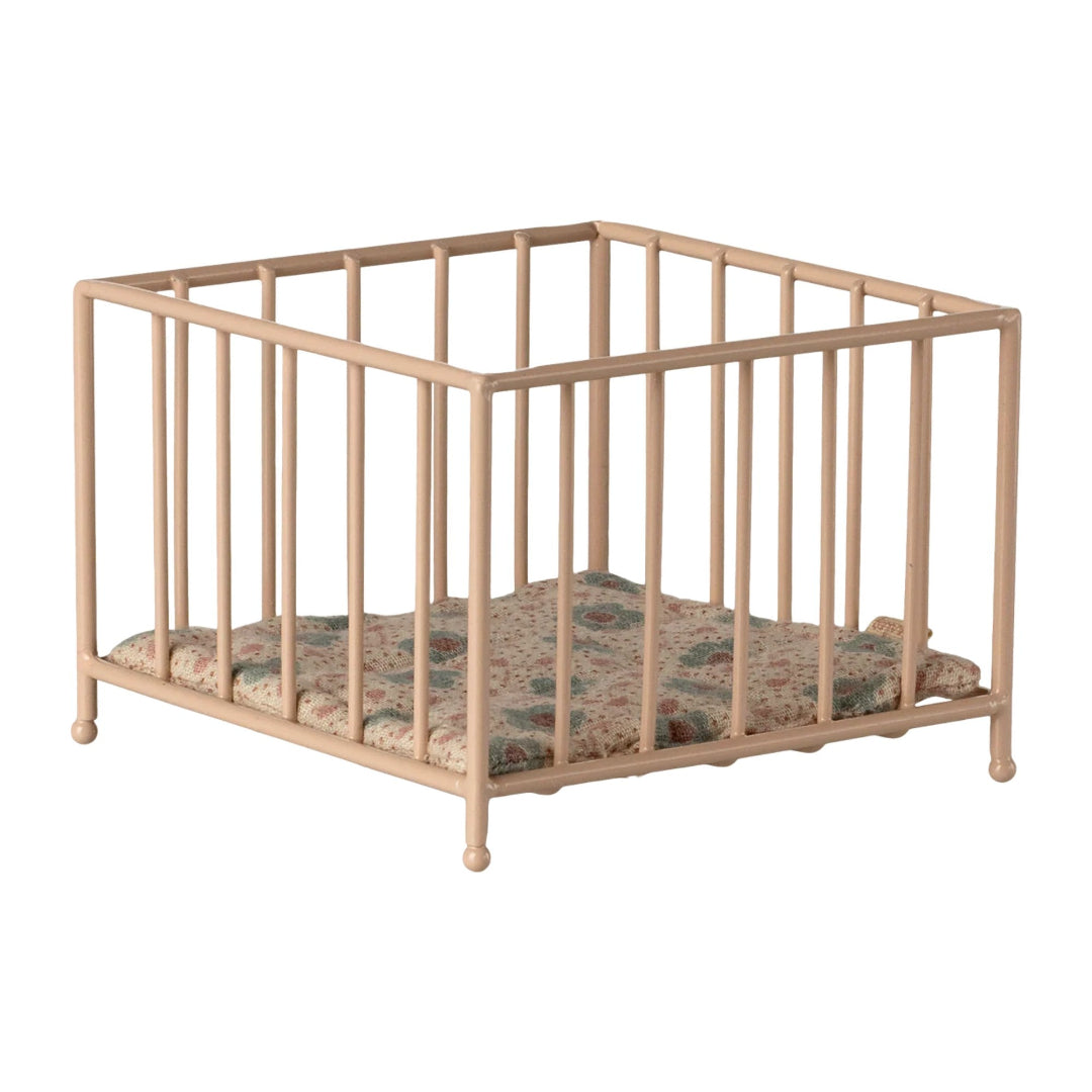Rose metal crib with a patterned mattress on a white background