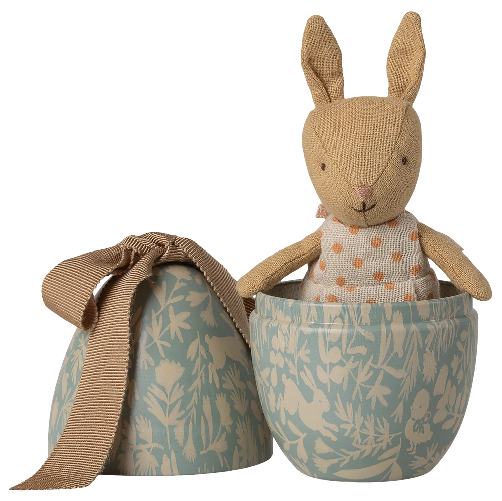 Stuffed rabbit toy in a tin egg on a white background