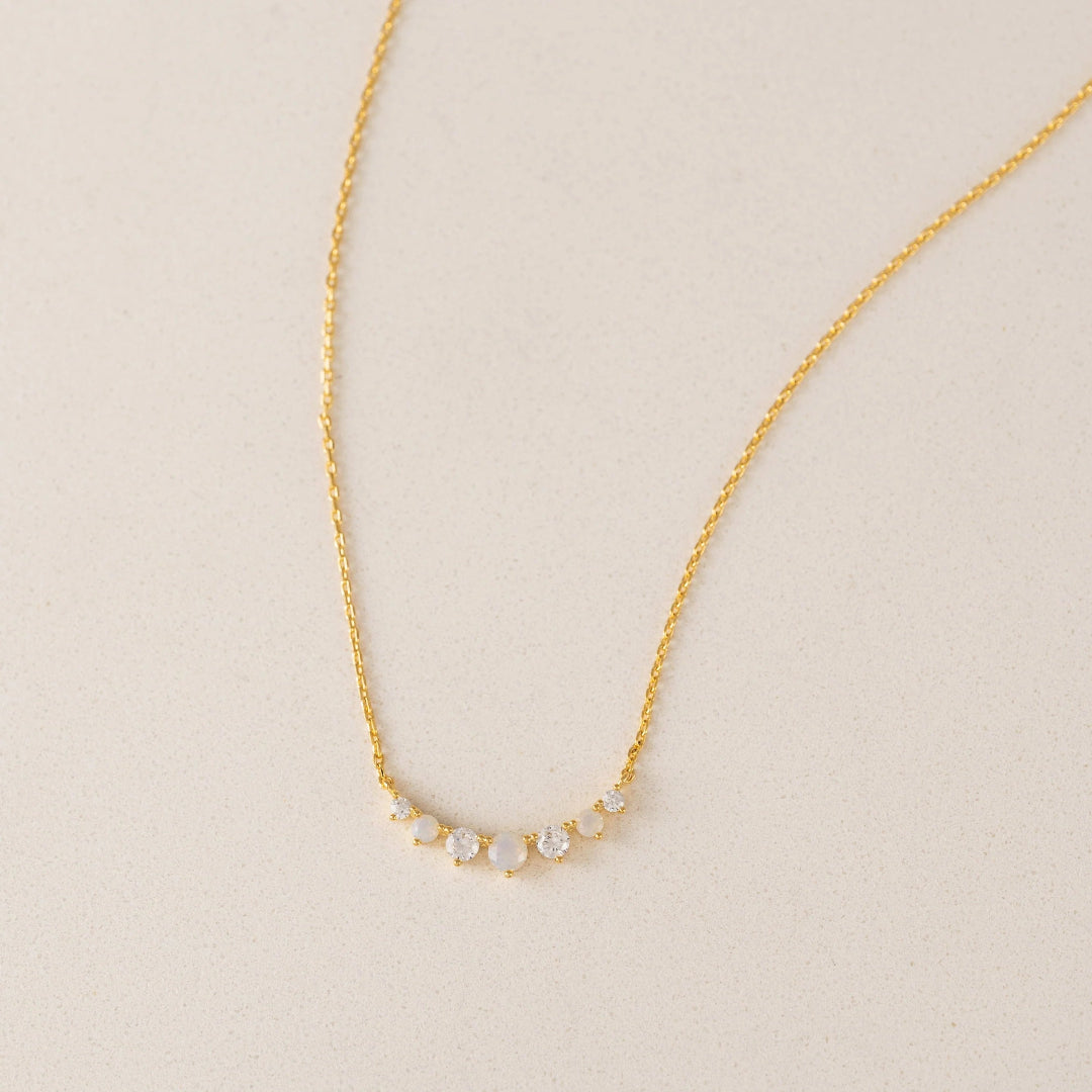 Gold necklace with small round stones on a beige background