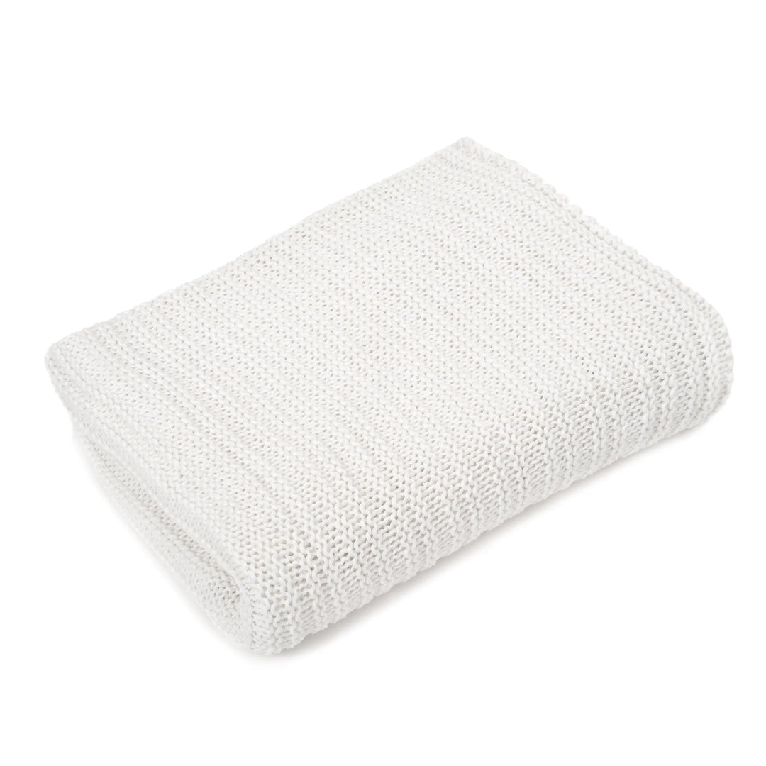 A folded white throw blanket with a textured knit pattern.