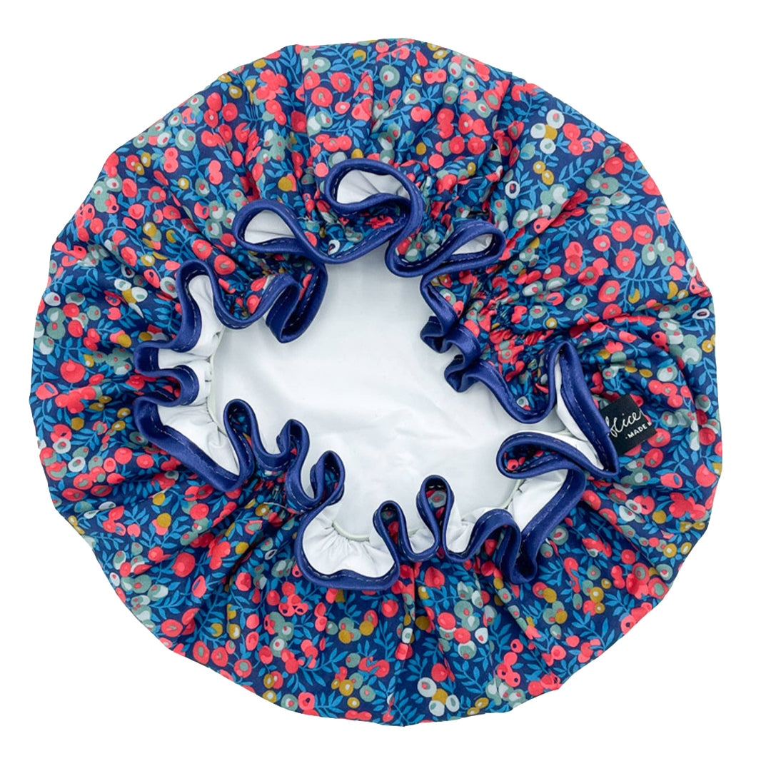 A floral patterned shower cap with blue ribbon edging.