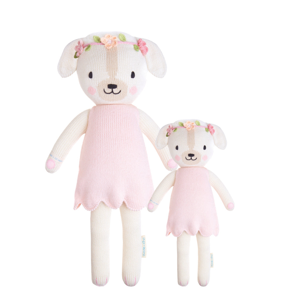 Two sizes of a hand-knit white dog doll with a pink dress and floral crown, made from cotton yarn.