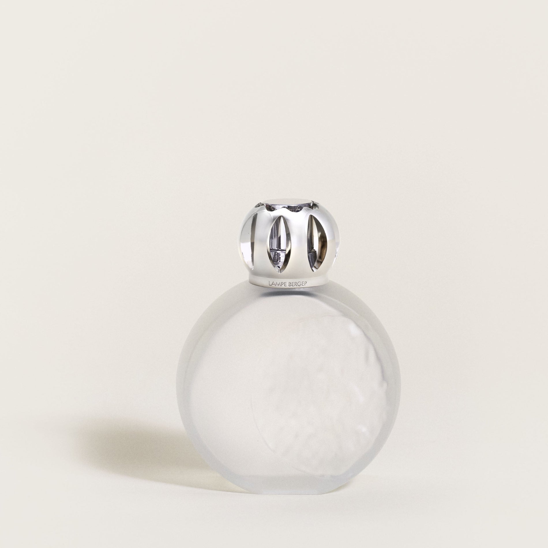 Clear glass bottle with silver cap on a light beige background