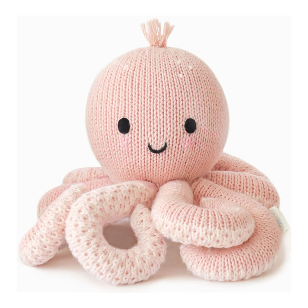 Knitted pink octopus toy with a smiley face on a white background