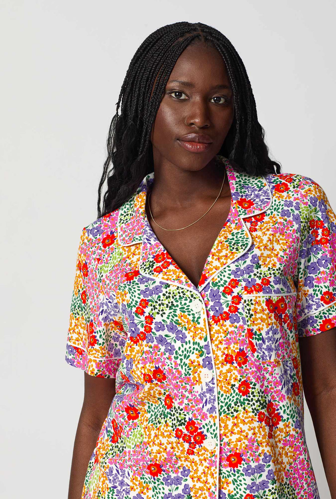Woman wearing a colorful floral shirt against a white background