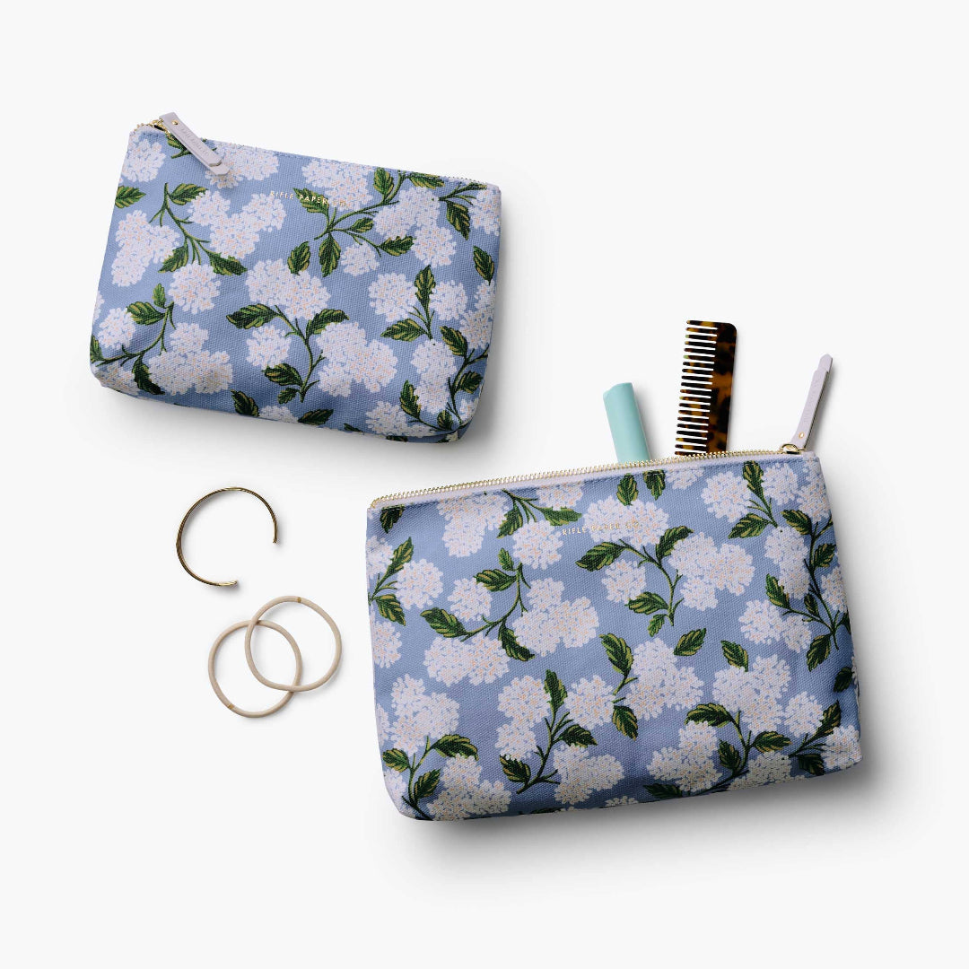 Two floral-patterned pouches with accessories on a white background