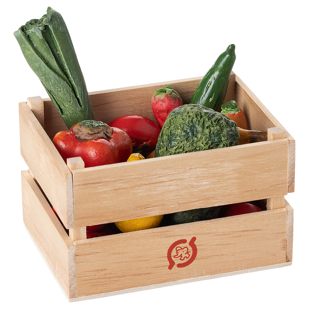 Wooden crate filled with toy vegetables on a white background