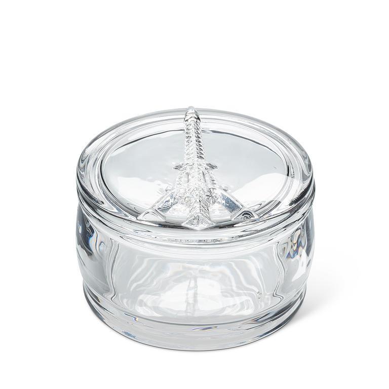 A clear glass keepsake box with a matching lid featuring a sculpted Eiffel Tower detail on top, set against a plain white background.
