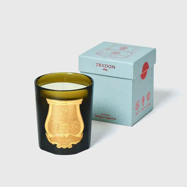 Decorative candle with gold interior and Trudon branded box on a light gray background