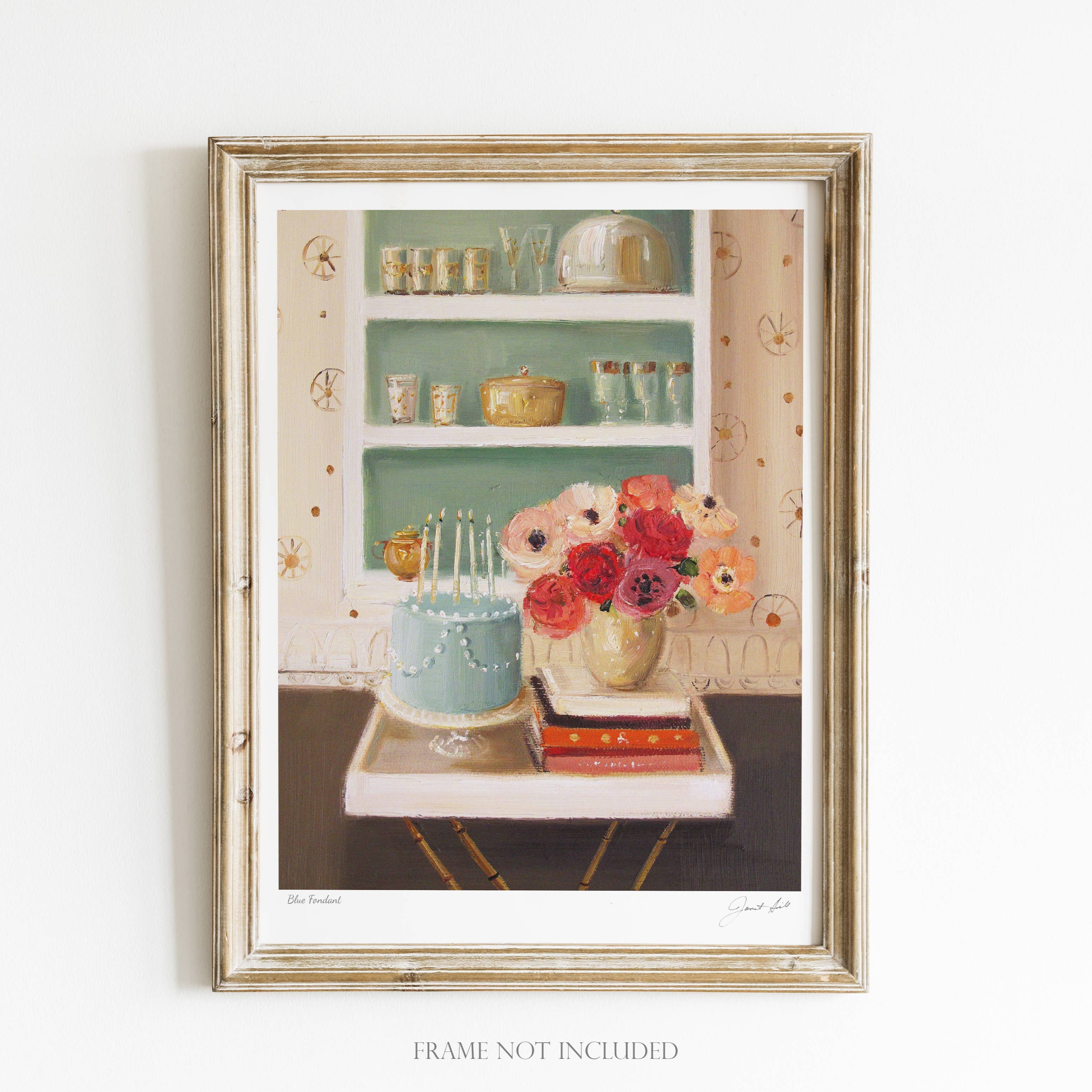 A framed art print featuring a kitchen scene with blue fondant, a vase with flowers, and a shelf with dishes and books. The frame is gold, and the artwork is signed by the artist.