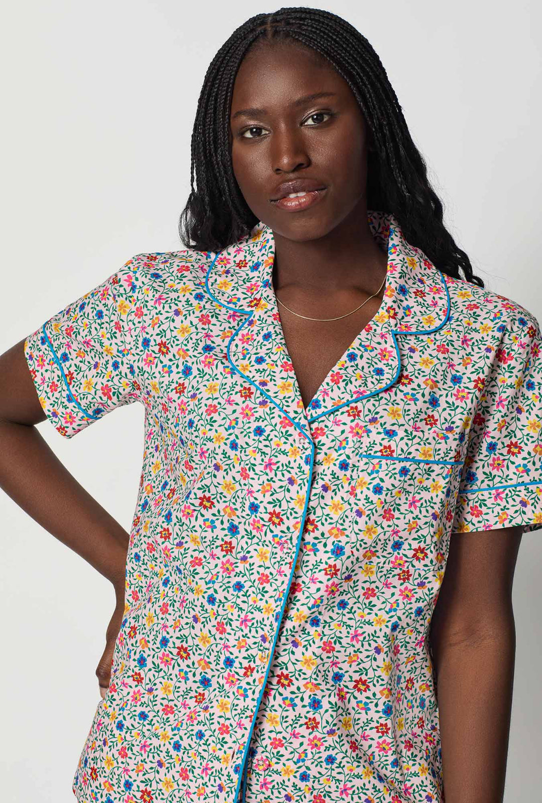 Woman wearing a colorful floral patterned shirt against a plain background