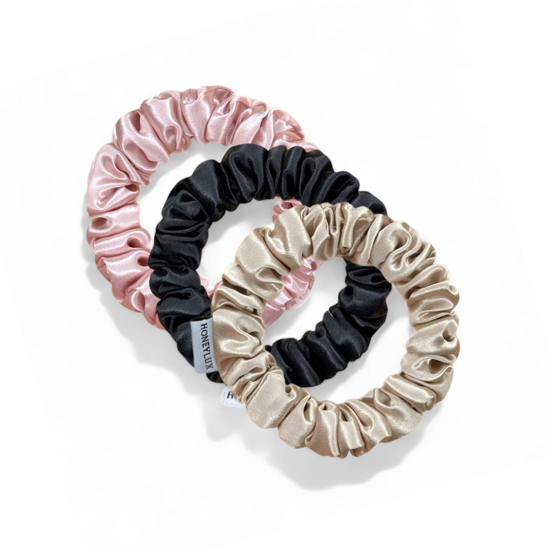 Set of three scrunchies in pink, black, and beige on a white background