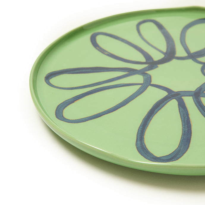 Green plate with blue design on a white background