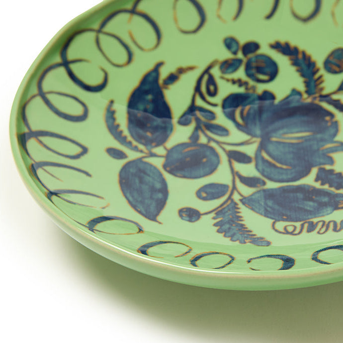 Green ceramic plate with blue floral patterns on a white background