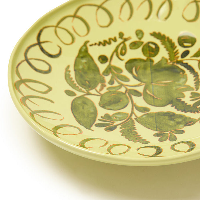 Decorative ceramic plate with green leaf patterns on a white background