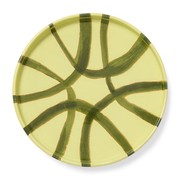 Round ceramic plate with green abstract design on a yellow background