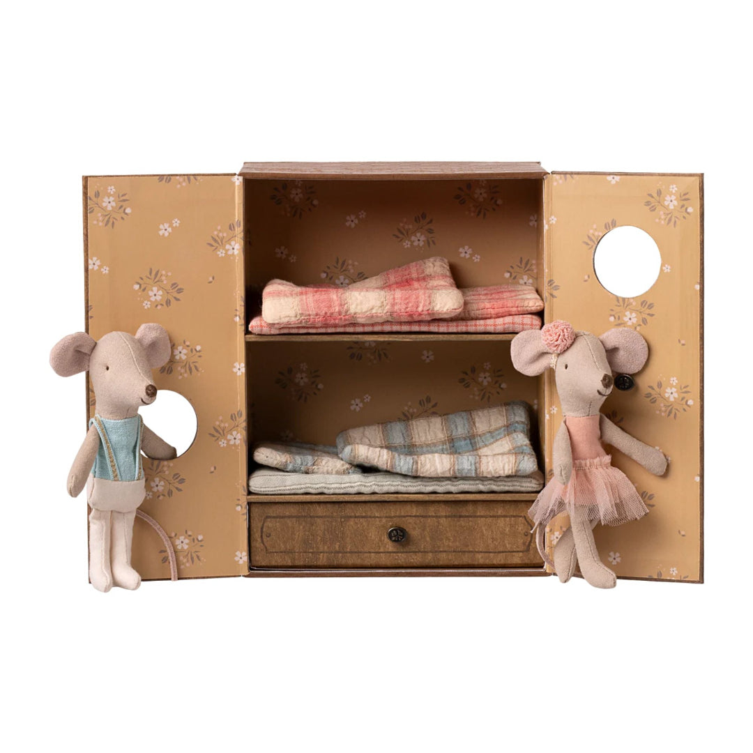 Toy cabinet with two plush mice and plaid blankets on a white background