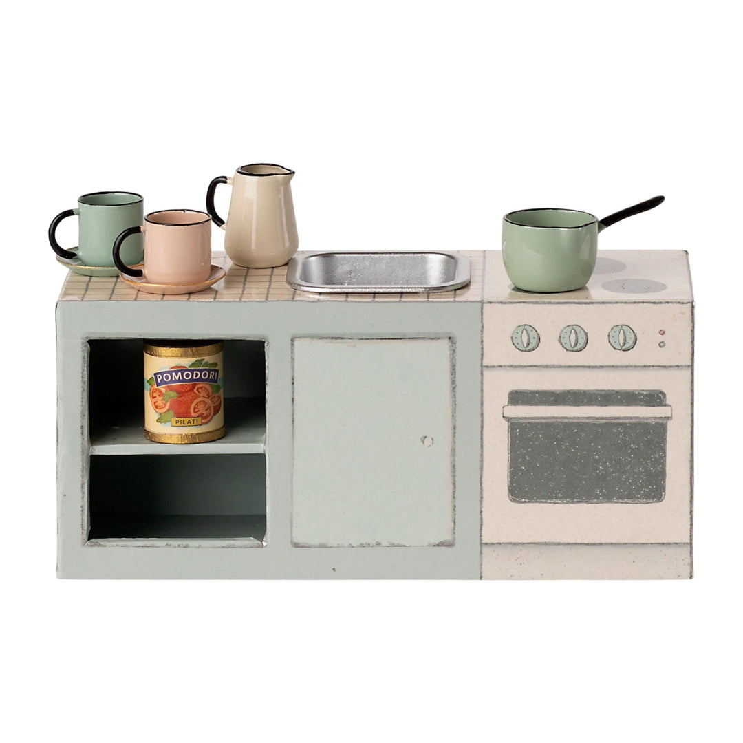 Miniature kitchen set with a stove, sink, and various items on a white background