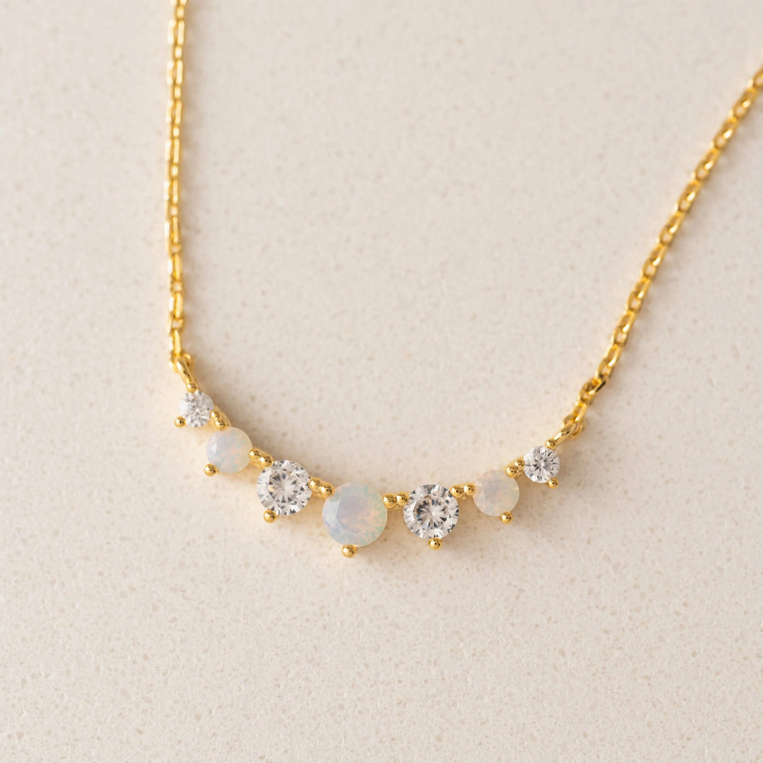 Gold necklace with gemstones on a beige background