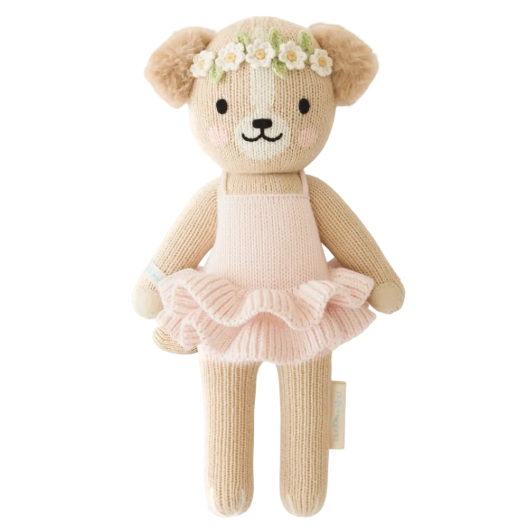 Knitted teddy bear in a pink dress with a flower crown on a white background