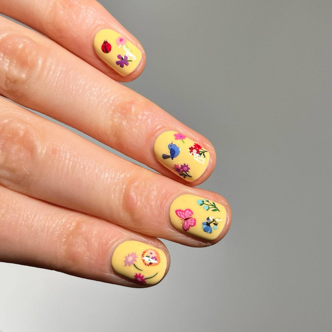 Nails with floral and butterfly designs on a yellow background