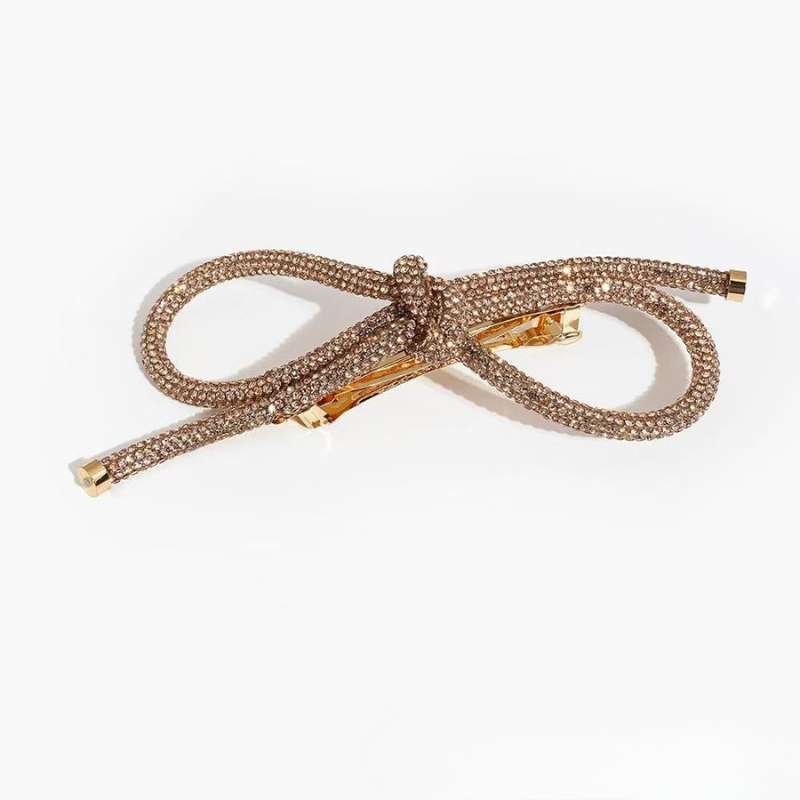 Gold bow-shaped hair clip on a white background