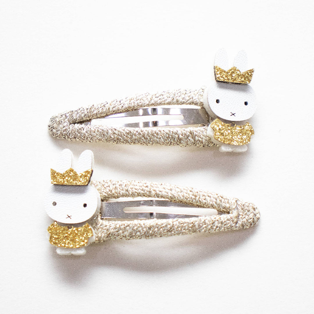 Two gold Miffy hair clips with crowns and dresses.