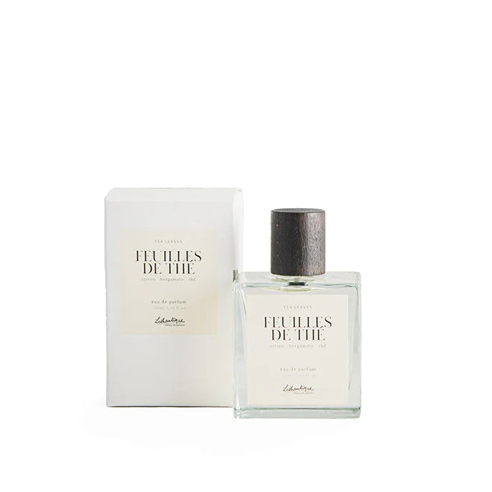 A bottle of Lothantique Eau de Parfum Tea Leaves with its packaging box. The bottle is clear and has a label with the brand name and the fragrance title.