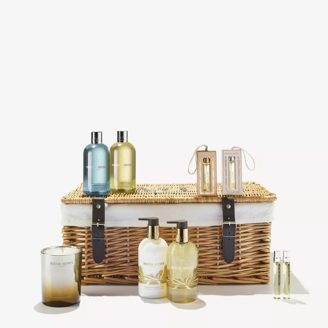 Bath and body products including bottles, a candle, and a basket on a white background