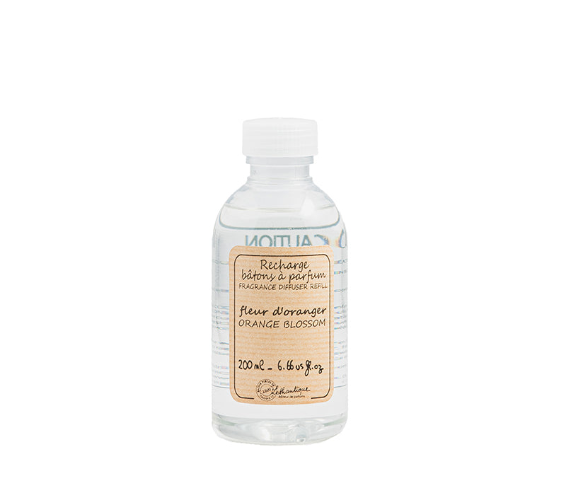 A clear bottle of Authentique Orange Blossom diffuser refill with a white label.