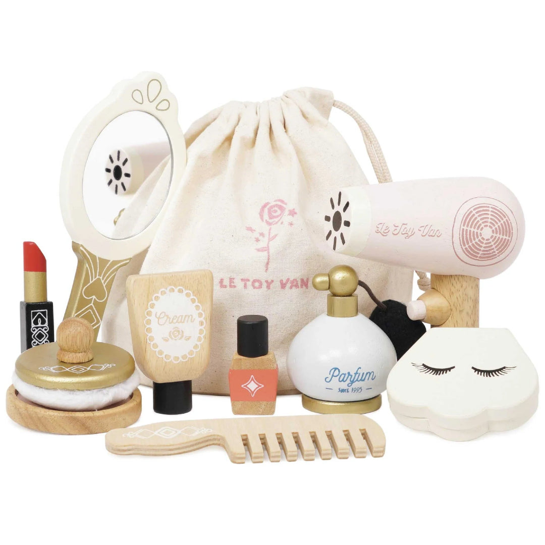 A collection of wooden pretend beauty products including a makeup bag, a mirror, a hair dryer, a comb, a nail varnish, a lipstick, a powder puff, a perfume bottle with a bulb atomizer, and a shell compact makeup kit, all with a matching natural cotton bag.