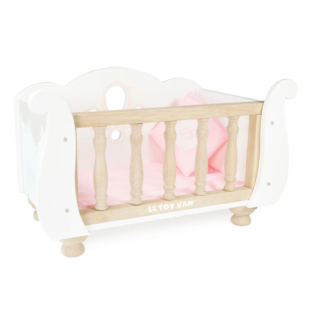 A white wooden toy cot with a pastel pink bedding set, designed for dolls and soft toy play.