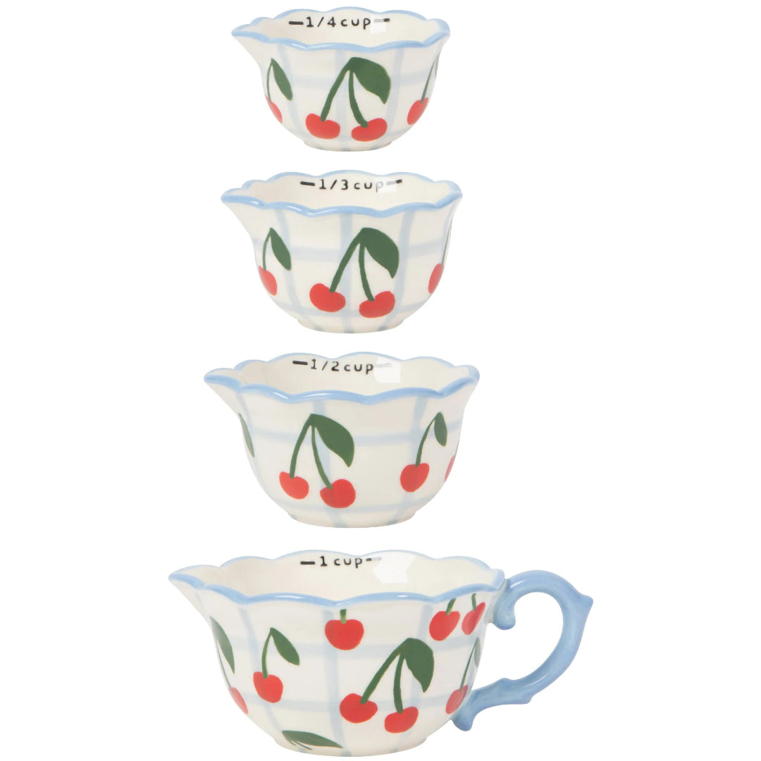 Set of four ceramic measuring cups with cherry design on a white background