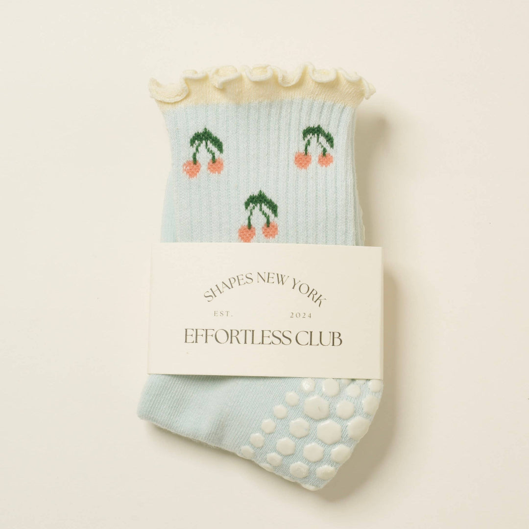 Pair of light blue socks with cherry design  on a beige background