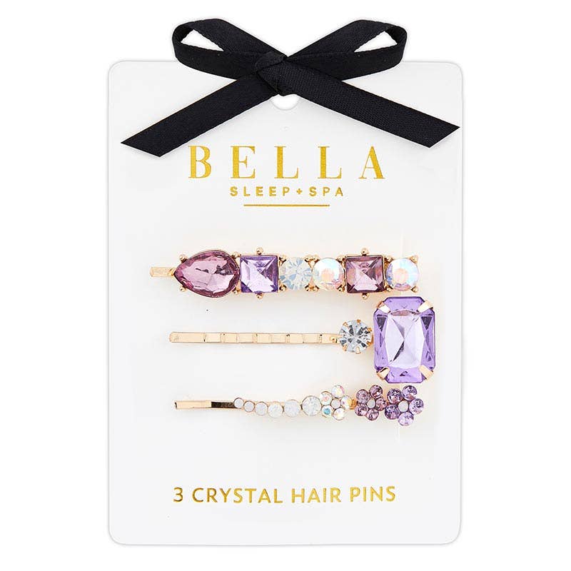 Three crystal hair pins with purple and clear jewels set in gold-colored mountings, packaged on a card with 'Bella Sleep + Spa' branding.