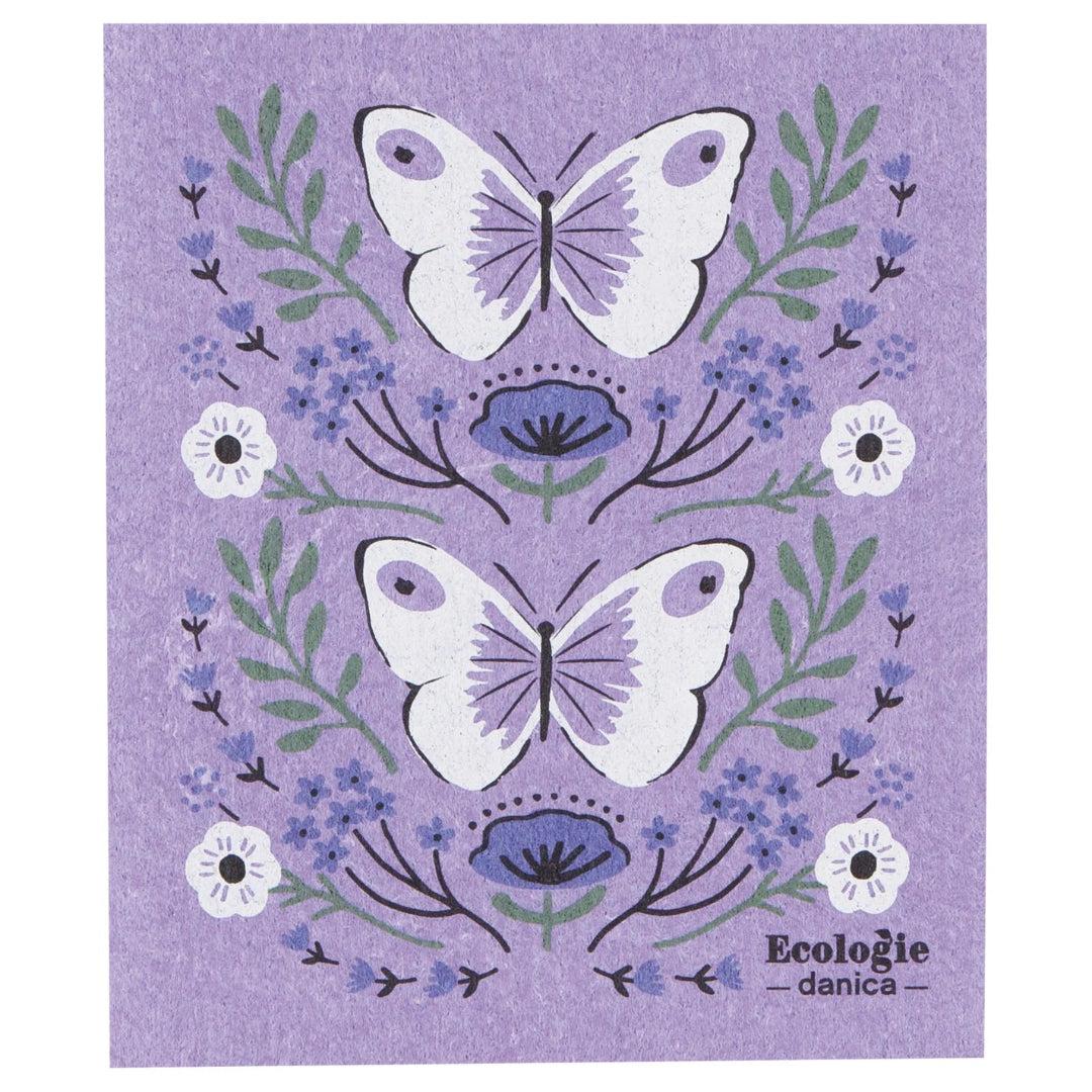 Swedish dishcloth with lavender background featuring two large white butterflies with light purple wing details, surrounded by green leaves, small blue flowers, and a few white blossoms.