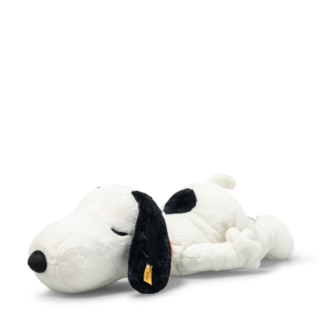 Plush toy Snoopy, sleeping on his belly on a white background