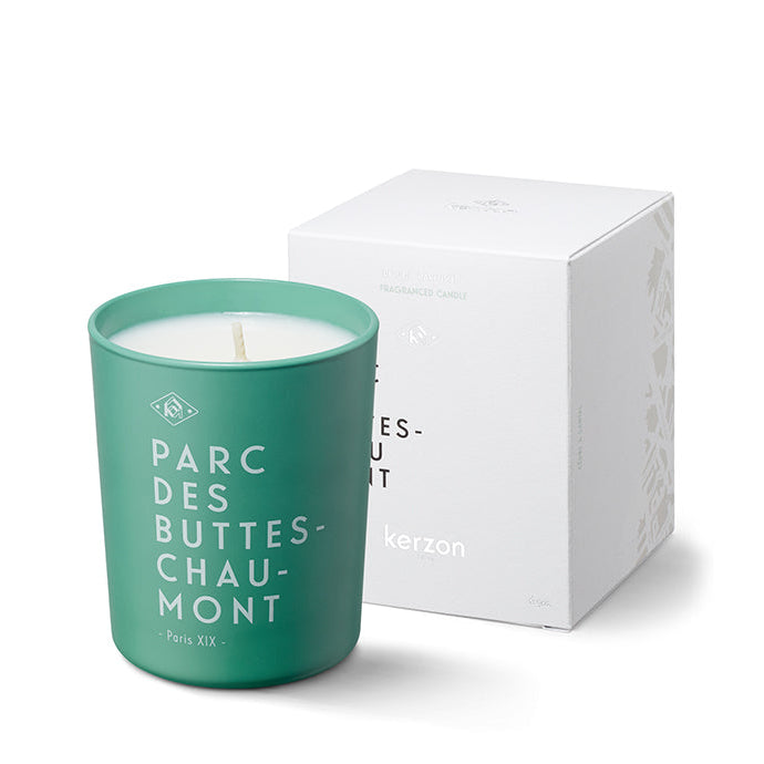 A green glass candle with white labeling that reads 'PARC DES BUTES-CHAUMONT', presented next to its white box packaging with the Kerzon brand logo.